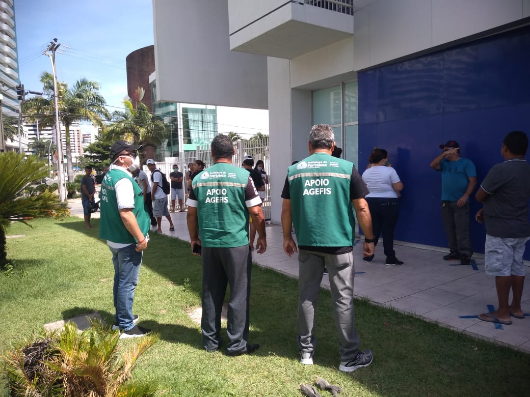 fiscal da prefeitura orienta fila na porta de um banco